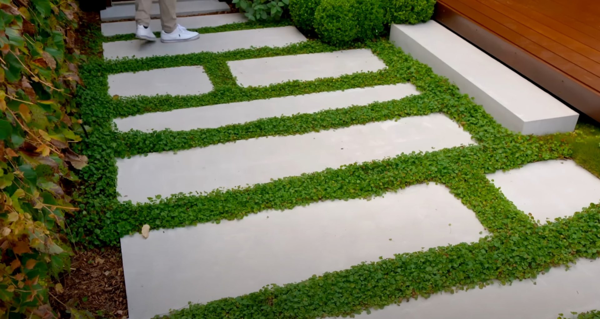 Modern concrete pavers with green moss strips creating geometric patterns